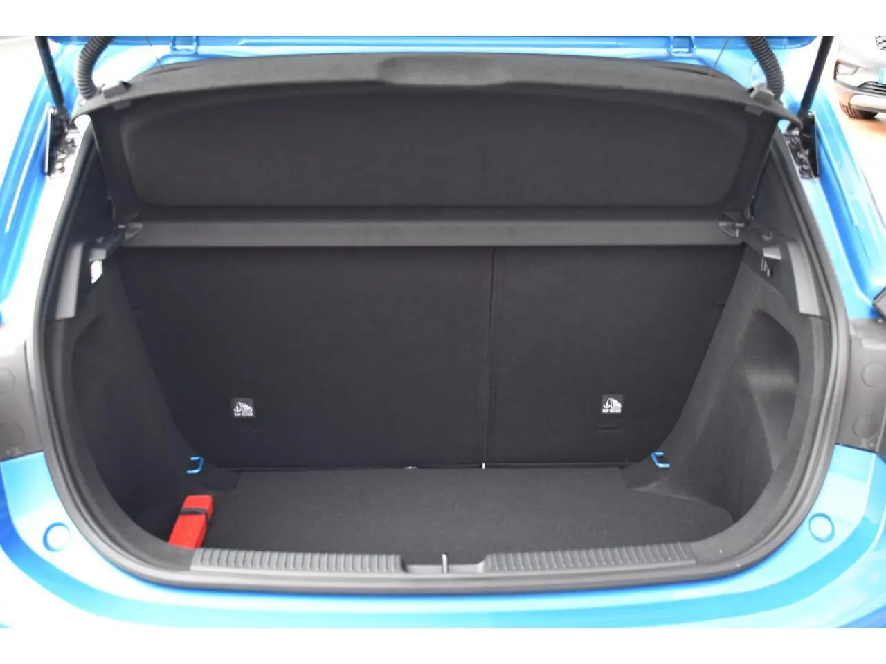 Coffre ouvert vu de l'arrière d'une MG3 1.5 L Hybrid+ bleu métallisé, montrant l'espace de chargement vide.