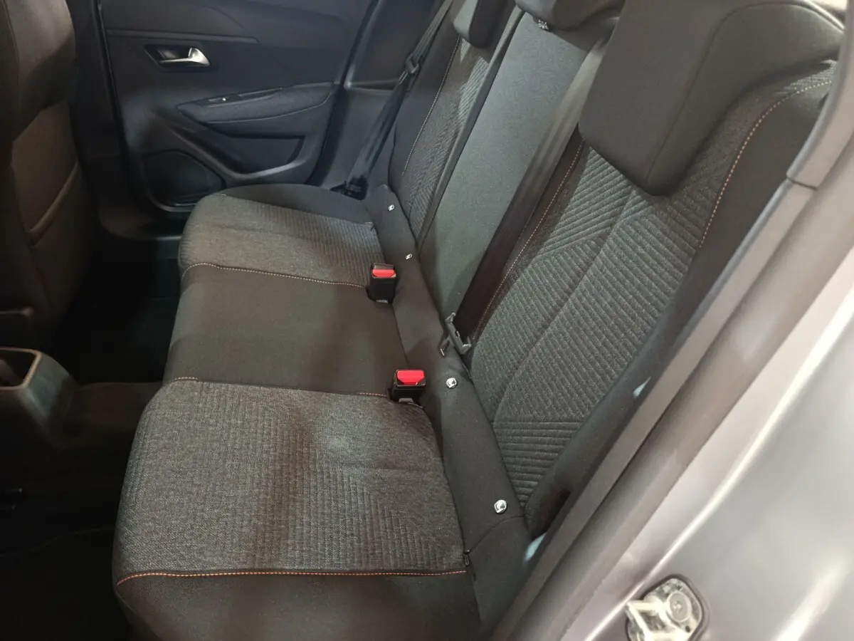 Vue latérale intérieure montrant la banquette arrière grise à trois places de la Peugeot 208 Hybrid 2025.