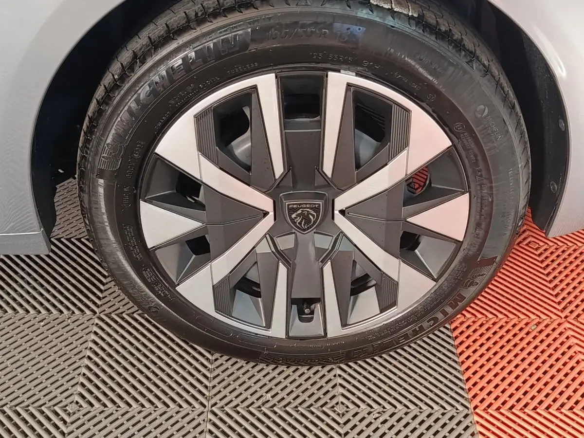 Gros plan sur la roue avant droite de la Peugeot 208 Hybrid 100 e-DCS6 Style gris clair avec jante alliage au design moderne.