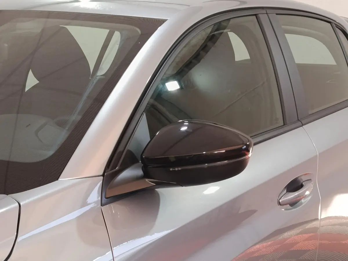 Gros plan sur le rétroviseur noir et la porte avant gauche d'une Peugeot 208 Hybrid gris clair, vue latérale.