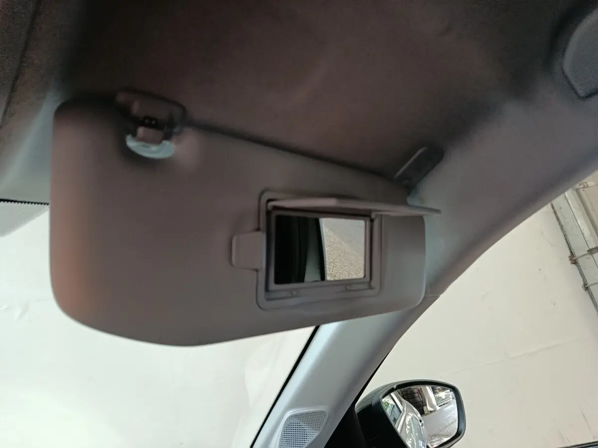 Détail intérieur montrant le pare-soleil avec miroir éclairant dans une Peugeot 208 Hybrid gris clair, côté conducteur.