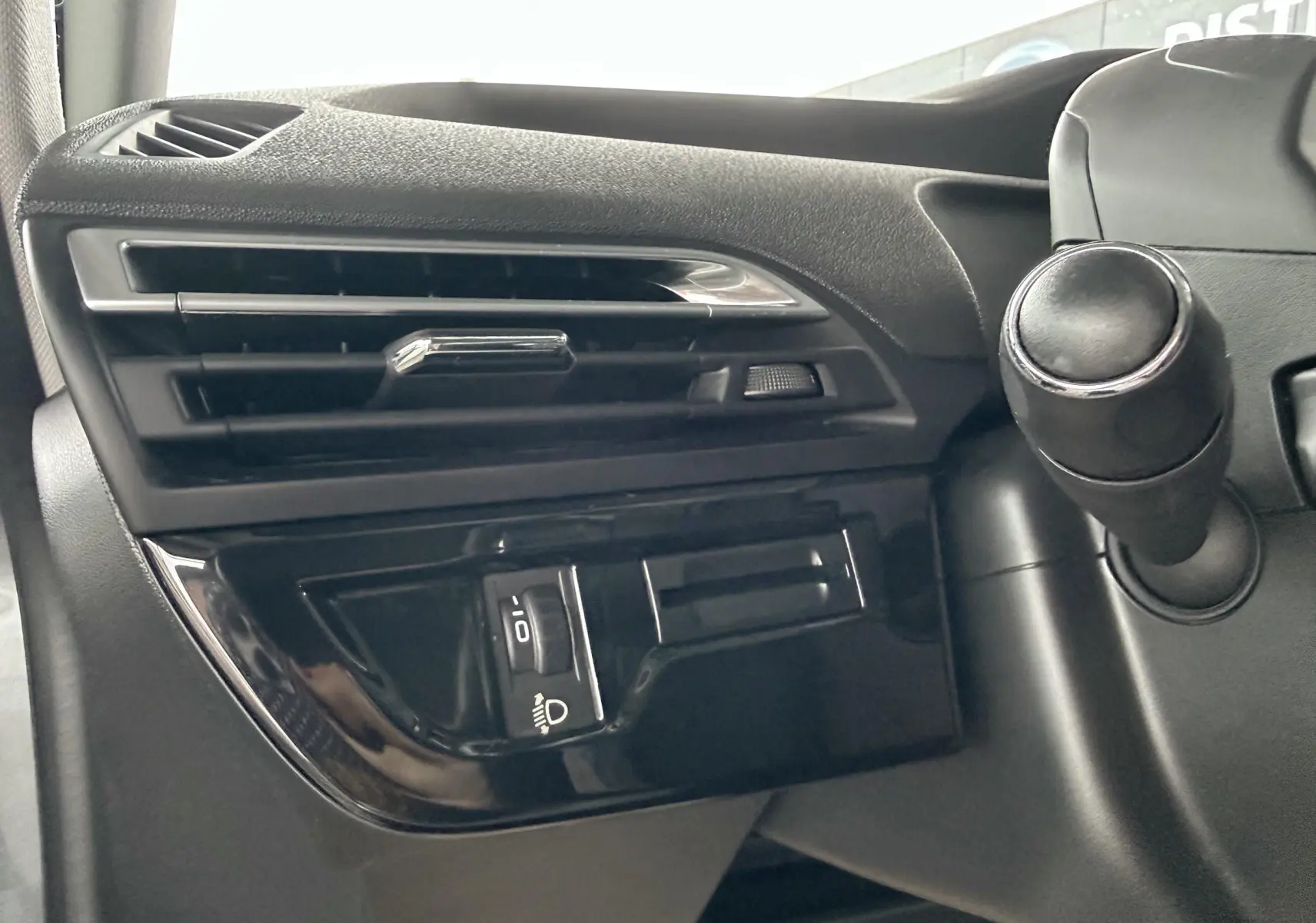 Détail de la console côté gauche du tableau de bord noir du Citroën C4 Picasso 2015, avec commande d'éclairage.