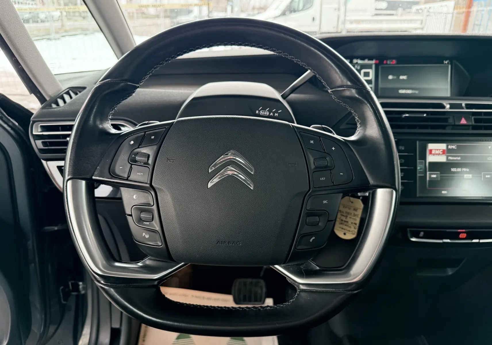 Vue centrée sur le volant noir avec commandes intégrées du Citroën C4 Picasso 2015, intérieur moderne et écran tactile visible.
