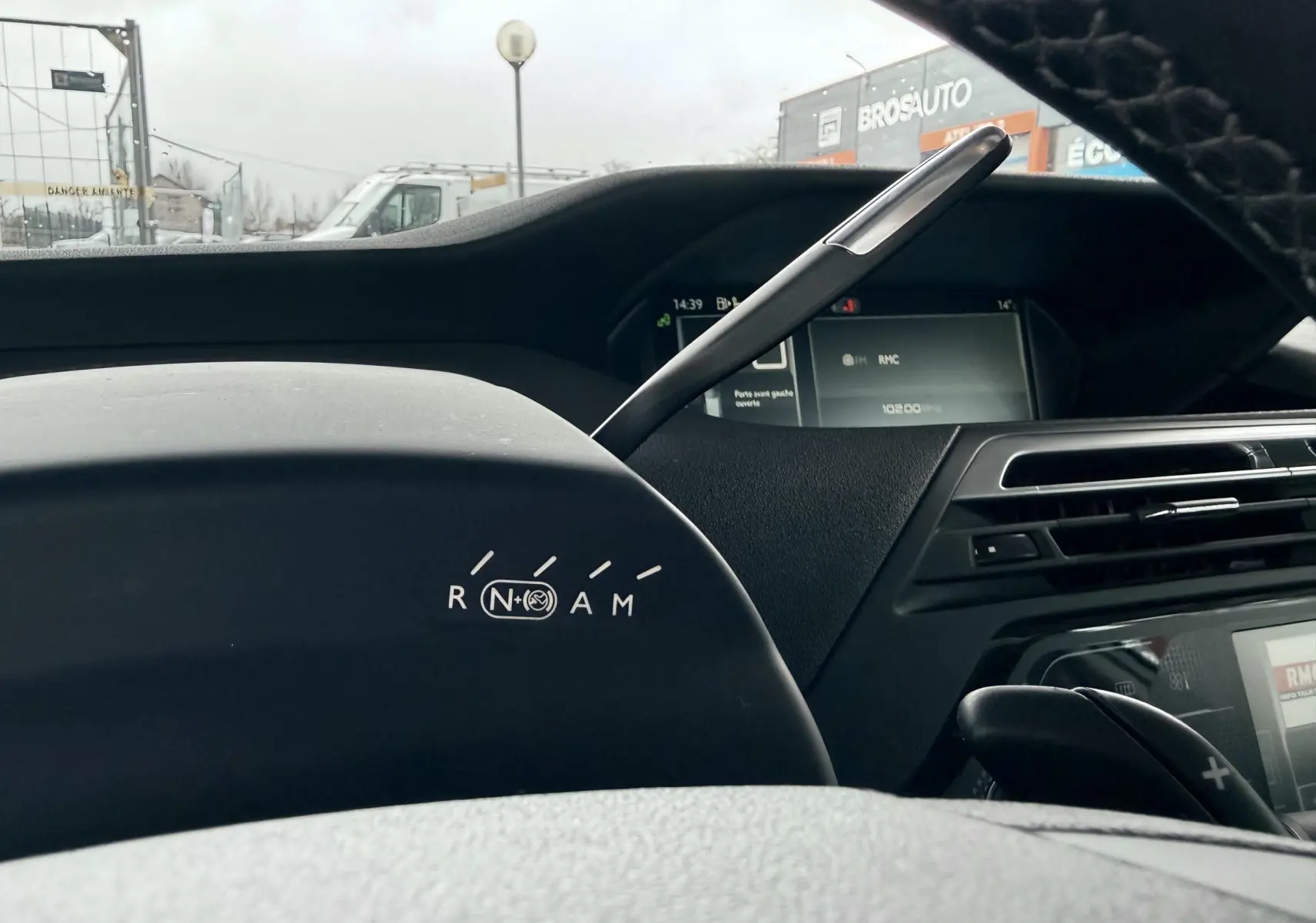 Vue intérieure du tableau de bord de la Citroën C4 Picasso 2015, montrant le levier de vitesses et l'écran digital.