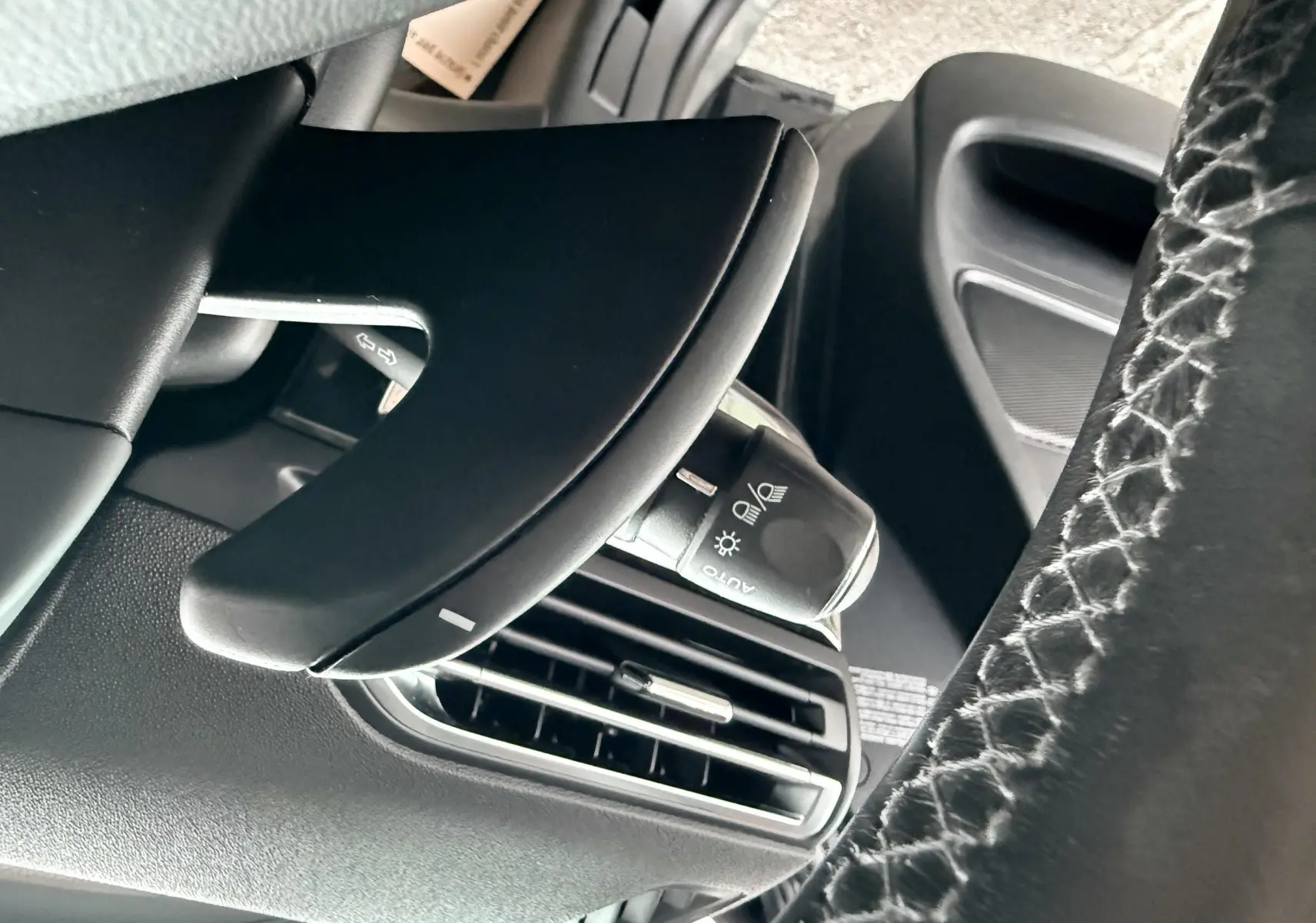 Gros plan sur la commande d'éclairage et la sortie d'air côté gauche du tableau de bord d'une Citroën C4 Picasso gris platinium.