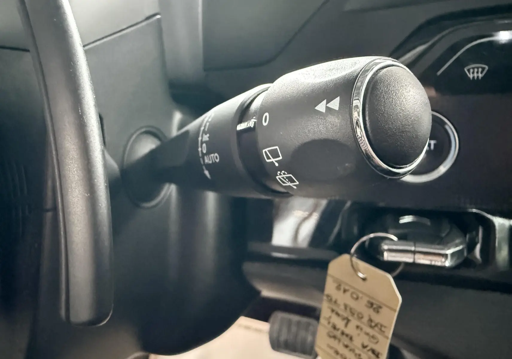 Gros plan sur la commande d’essuie-glace à gauche du volant dans l’habitacle sombre d’une Citroën C4 Picasso gris platinium.