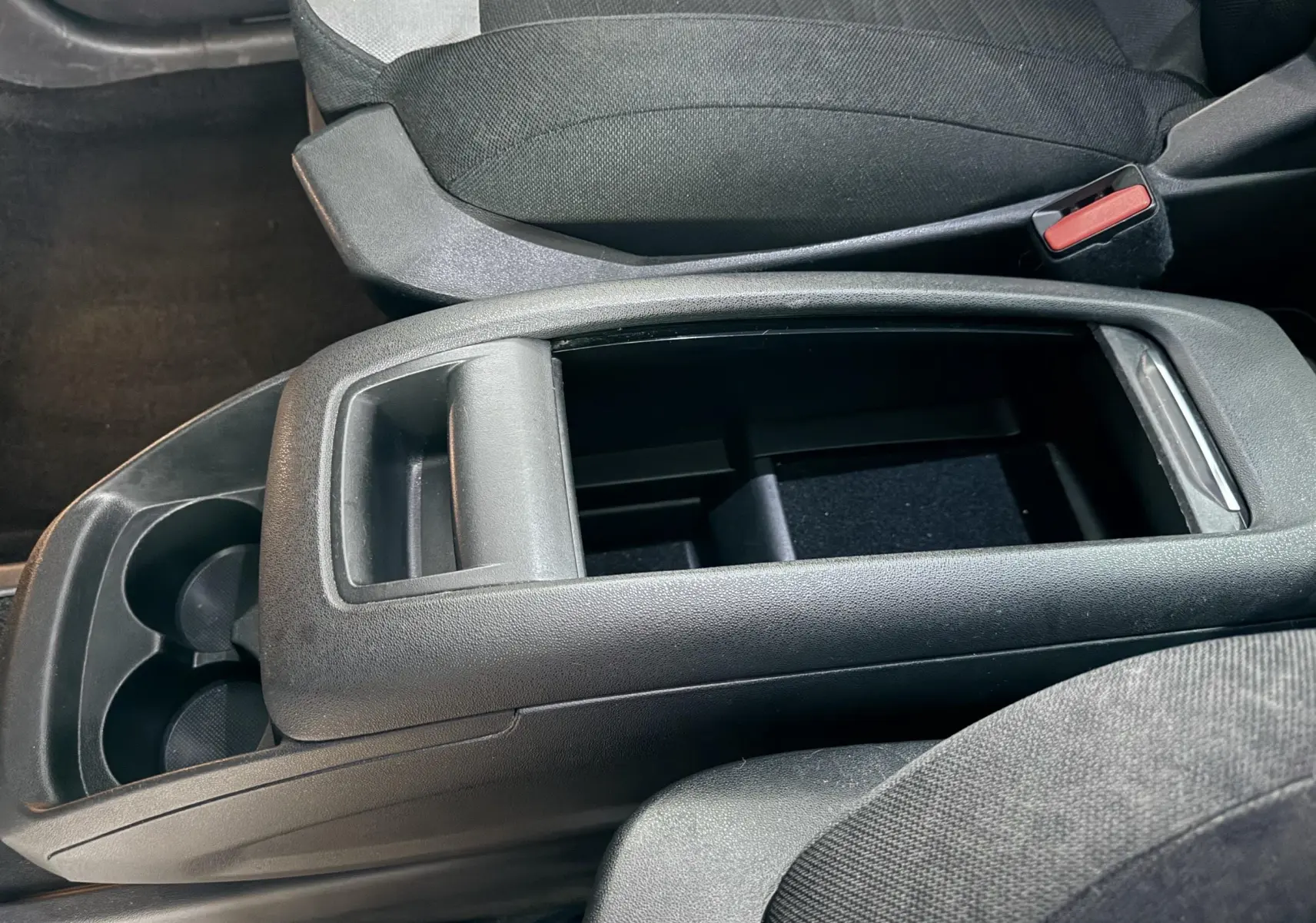 Vue rapprochée de la console centrale noire avec rangement ouvert et porte-gobelets du Citroën C4 Picasso 2015.