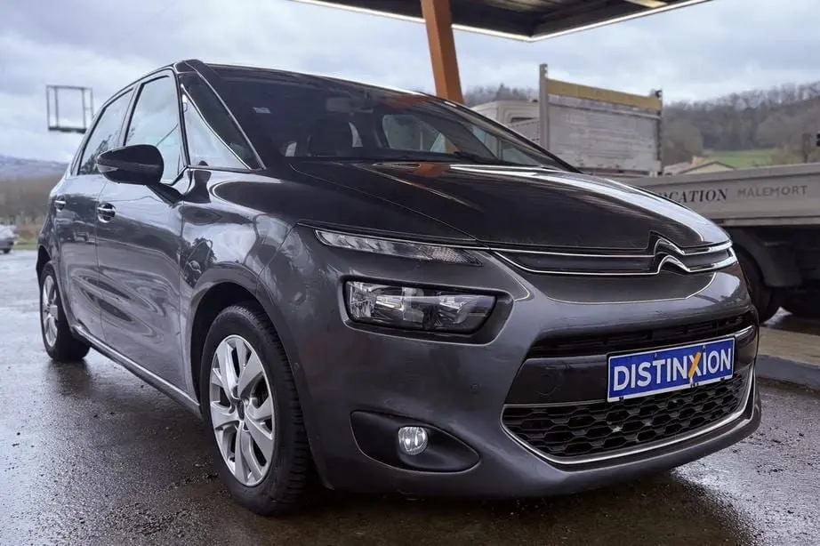 Vue 3/4 avant gauche d'une Citroën C4 Picasso gris platinium métal avec calandre distinctive et plaque Distinxion.