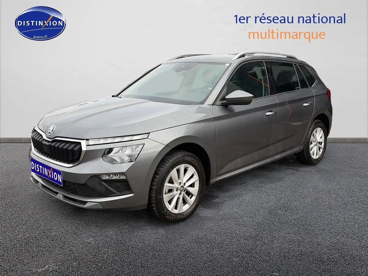 Vue 3/4 avant d'un Skoda Kamiq gris avec calandre noire et jantes alu sur fond neutre.