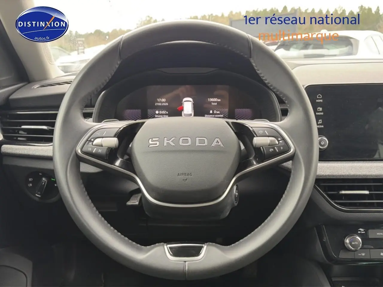 Vue centrée sur le volant cuir noir SKODA avec tableau de bord numérique et écran tactile à droite.