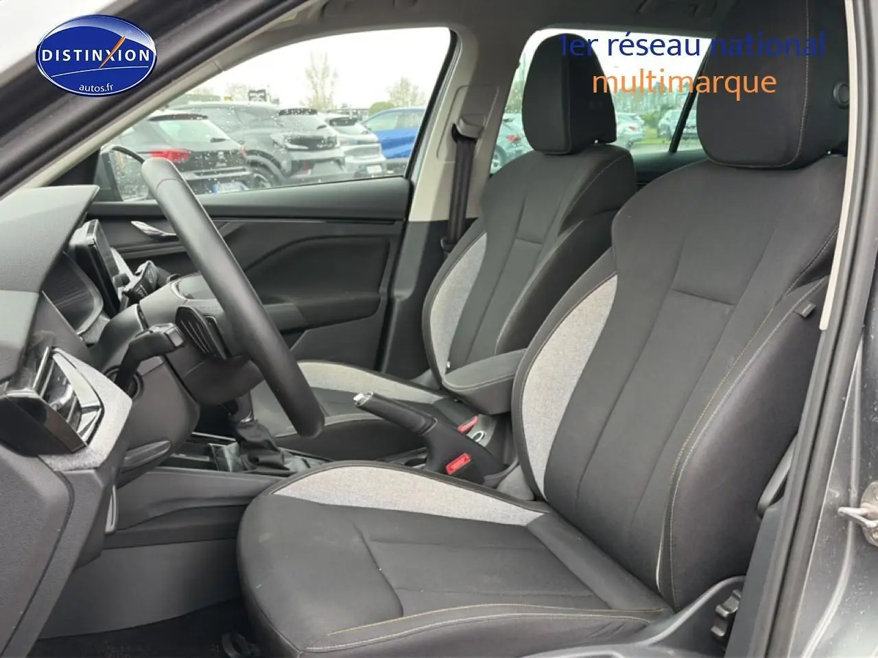 Vue intérieure côté conducteur du Skoda Kamiq gris 2025, sièges tissu bicolores noirs et gris avec coutures contrastées.