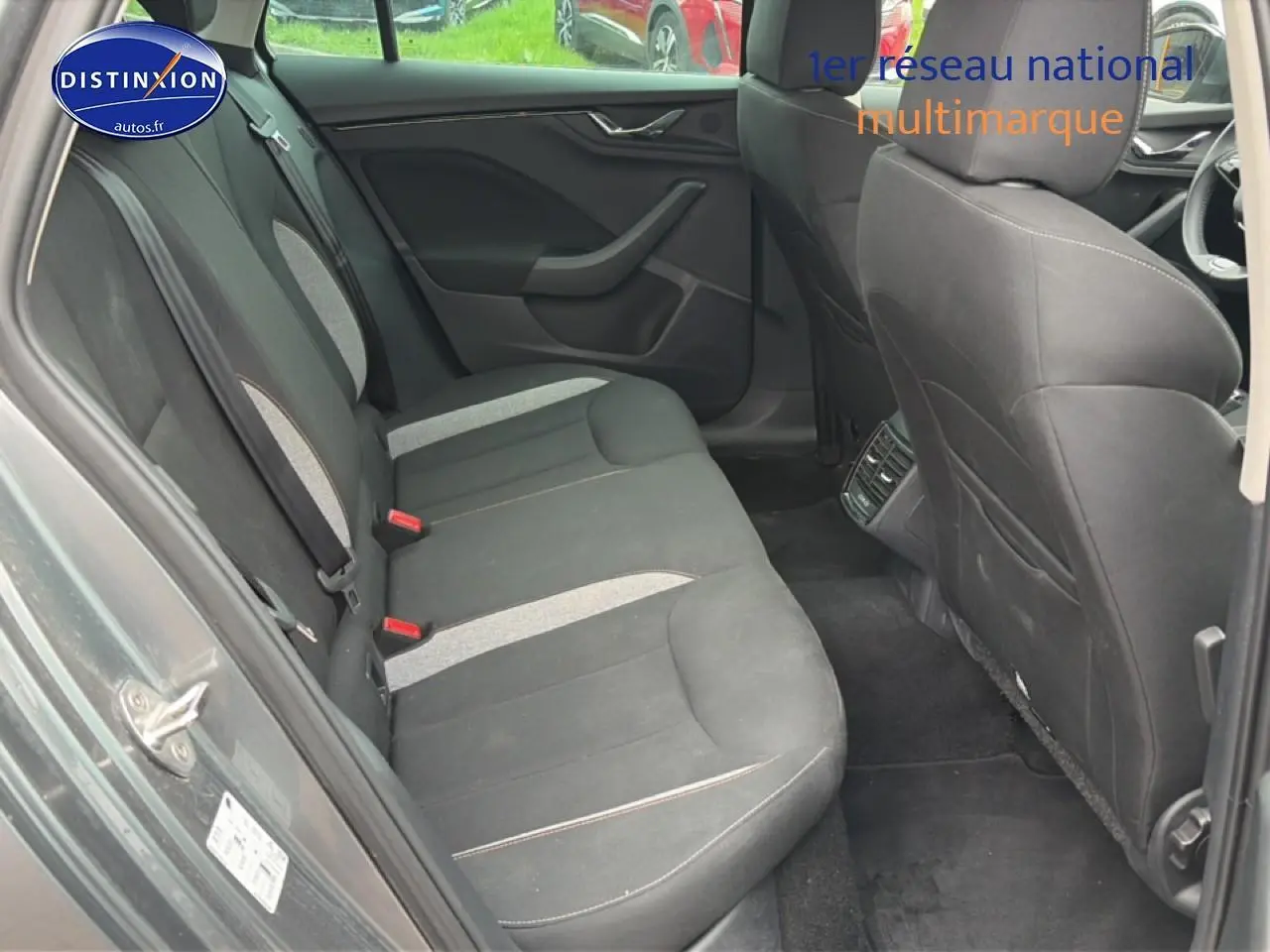 Vue intérieure arrière côté gauche du Skoda Kamiq gris, montrant les sièges tissu bicolores et les aérateurs arrière.