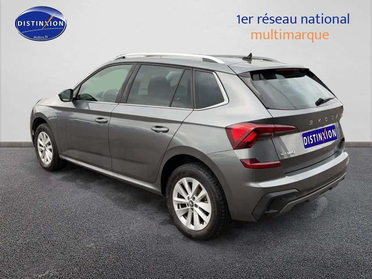 Vue 3/4 arrière droite d'un Skoda Kamiq gris 2025 avec barres de toit et feux arrière LED distinctifs.