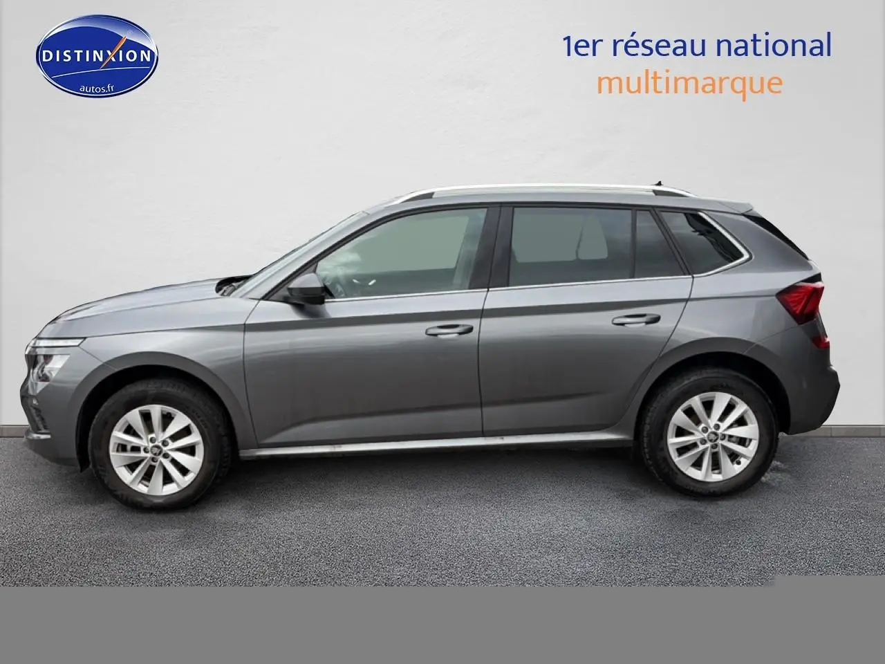 Profil côté gauche d'un Skoda Kamiq gris 2025 avec jantes alu et barres de toit visibles.