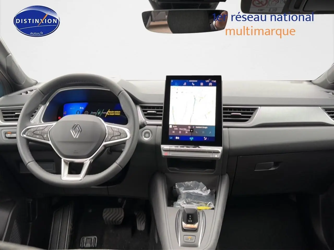 Vue intérieure avant du tableau de bord gris du Renault Symbioz 1.8 e-tech avec écran tactile vertical et volant multifonction.