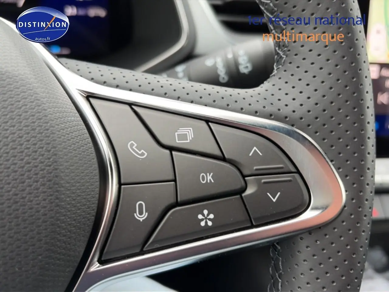 Gros plan sur les commandes noires du volant perforé côté gauche du Renault Symbioz bleu mercure.