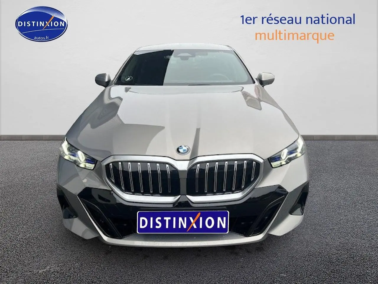 Vue avant d'une BMW Série 5 G60 gris métallisé avec calandre imposante et phares LED allumés.