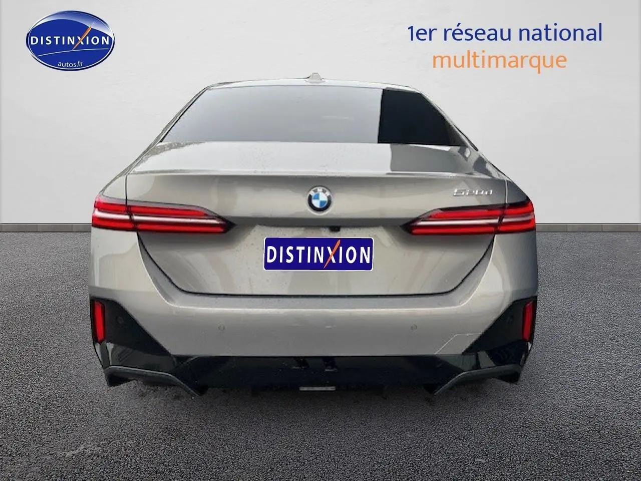 Vue arrière d'une BMW Série 5 gris clair (520da M Sport) avec feux LED et logo distinctif au centre.
