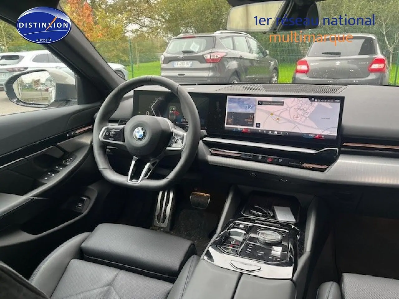 Vue intérieure côté conducteur de la BMW Série 5 G60 520da 2024, tableau de bord moderne avec écran large tactile.