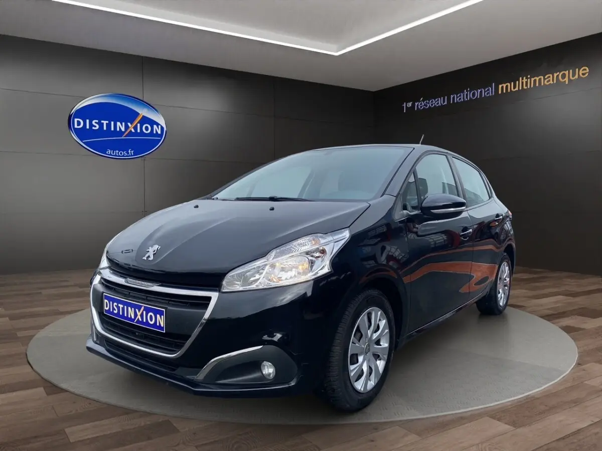 Peugeot 208 Affaire noir vue 3/4 avant droit, avec phares allumés et jantes argentées en showroom.