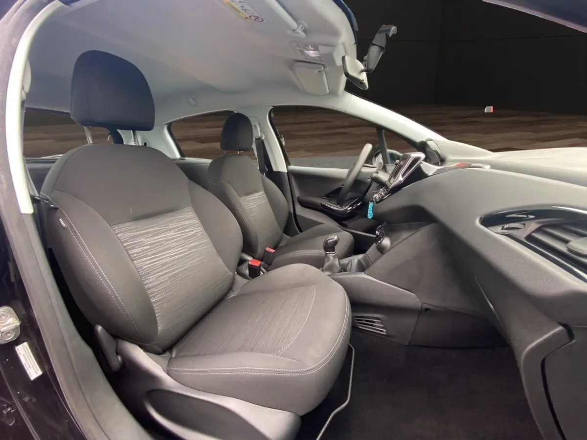 Intérieur avant droit de la Peugeot 208 AFFAIRE noire, sièges tissu gris et tableau de bord avec écran tactile.