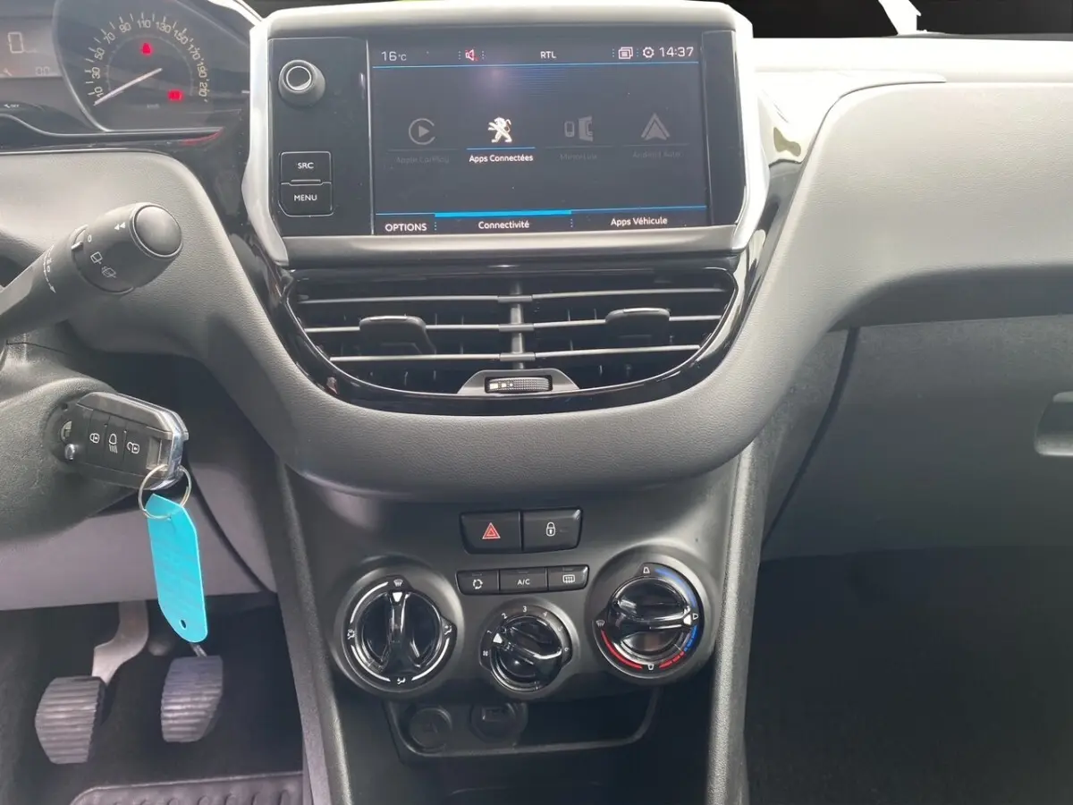 Vue rapprochée du tableau de bord noir de la Peugeot 208 AFFAIRE 2019 avec écran tactile et commandes manuelles de climatisation.