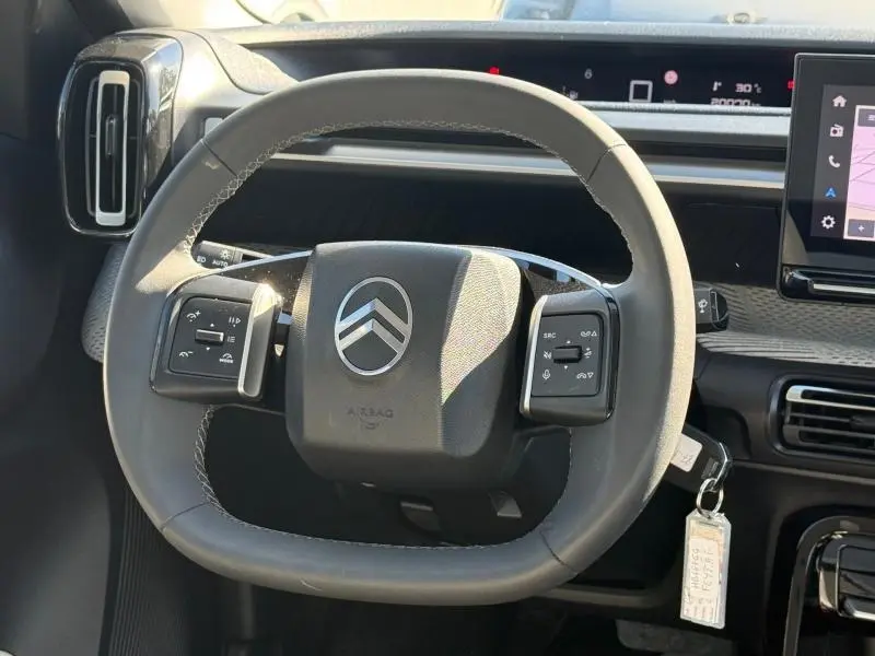 Vue rapprochée du volant noir de la Citroën C3 2025 avec commandes intégrées et tableau de bord numérique.