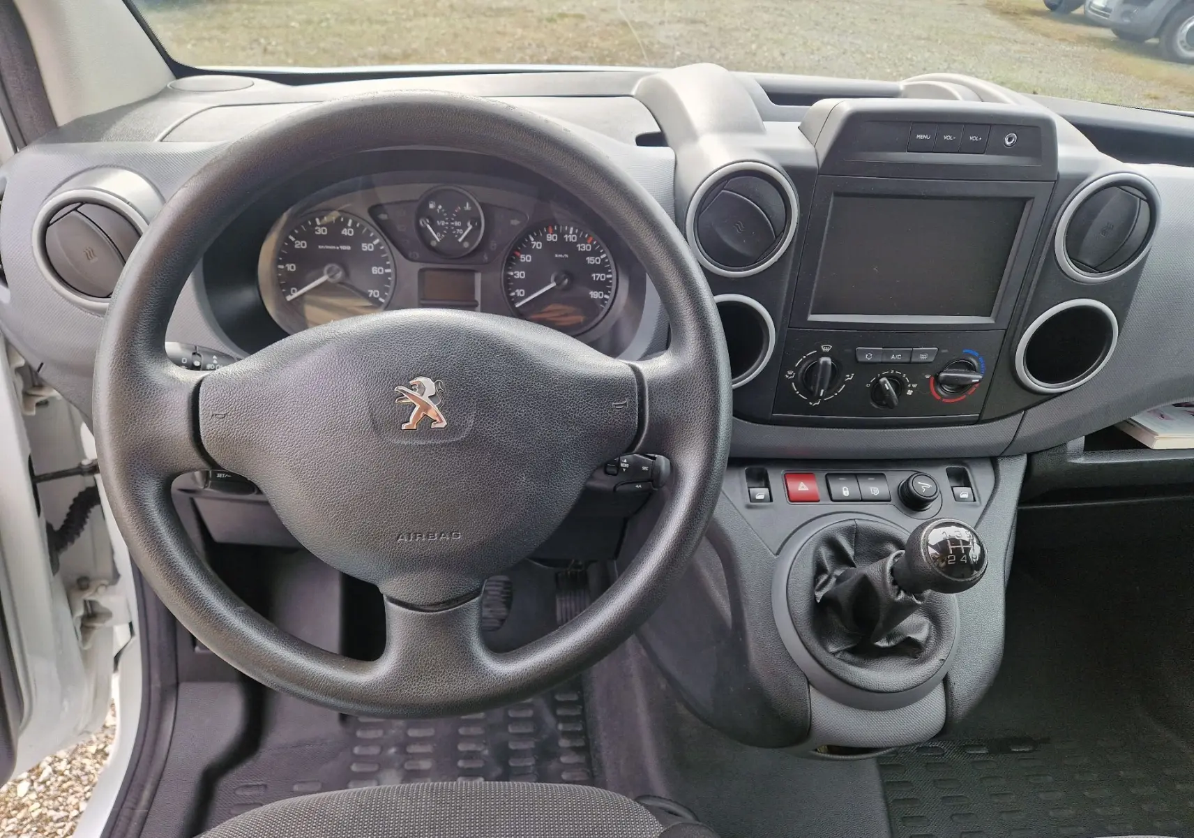 Vue intérieure du tableau de bord du Peugeot Partner blanc 2017, avec volant, levier de vitesse manuel et écran central éteint.