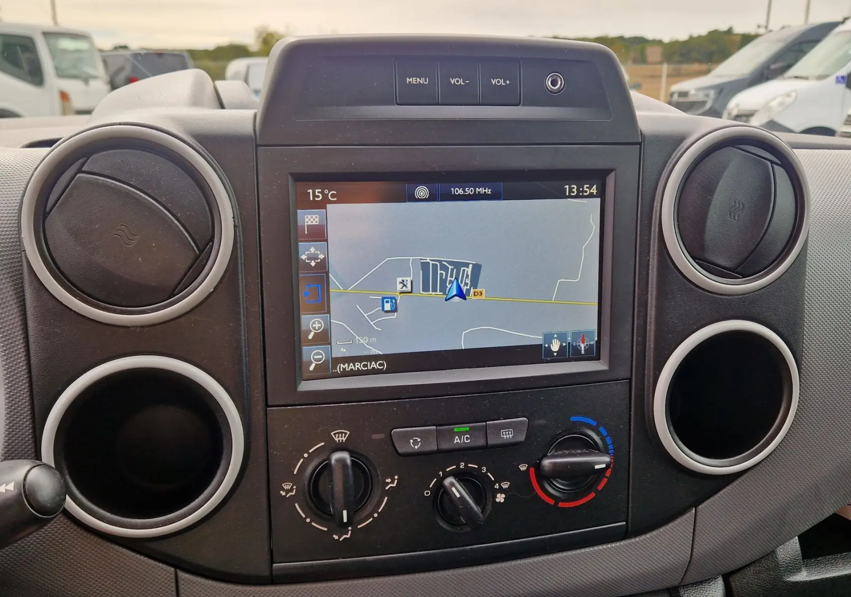 Vue rapprochée du tableau de bord du Peugeot Partner blanc 2017, avec écran GPS et commandes de climatisation visibles.