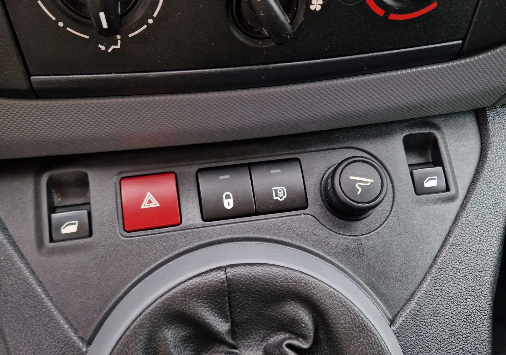 Gros plan sur la console centrale du Peugeot Partner blanc 2017, montrant les boutons de verrouillage, warning et réglage des rétroviseurs.