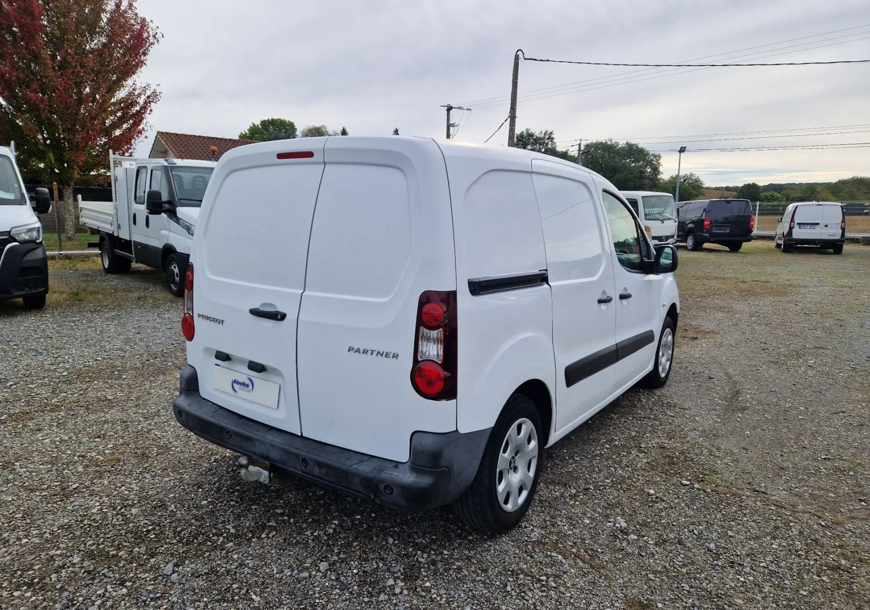 Vue 3/4 arrière droite d’un Peugeot Partner blanc 2017 utilitaire avec portes arrière battantes et attelage visible.