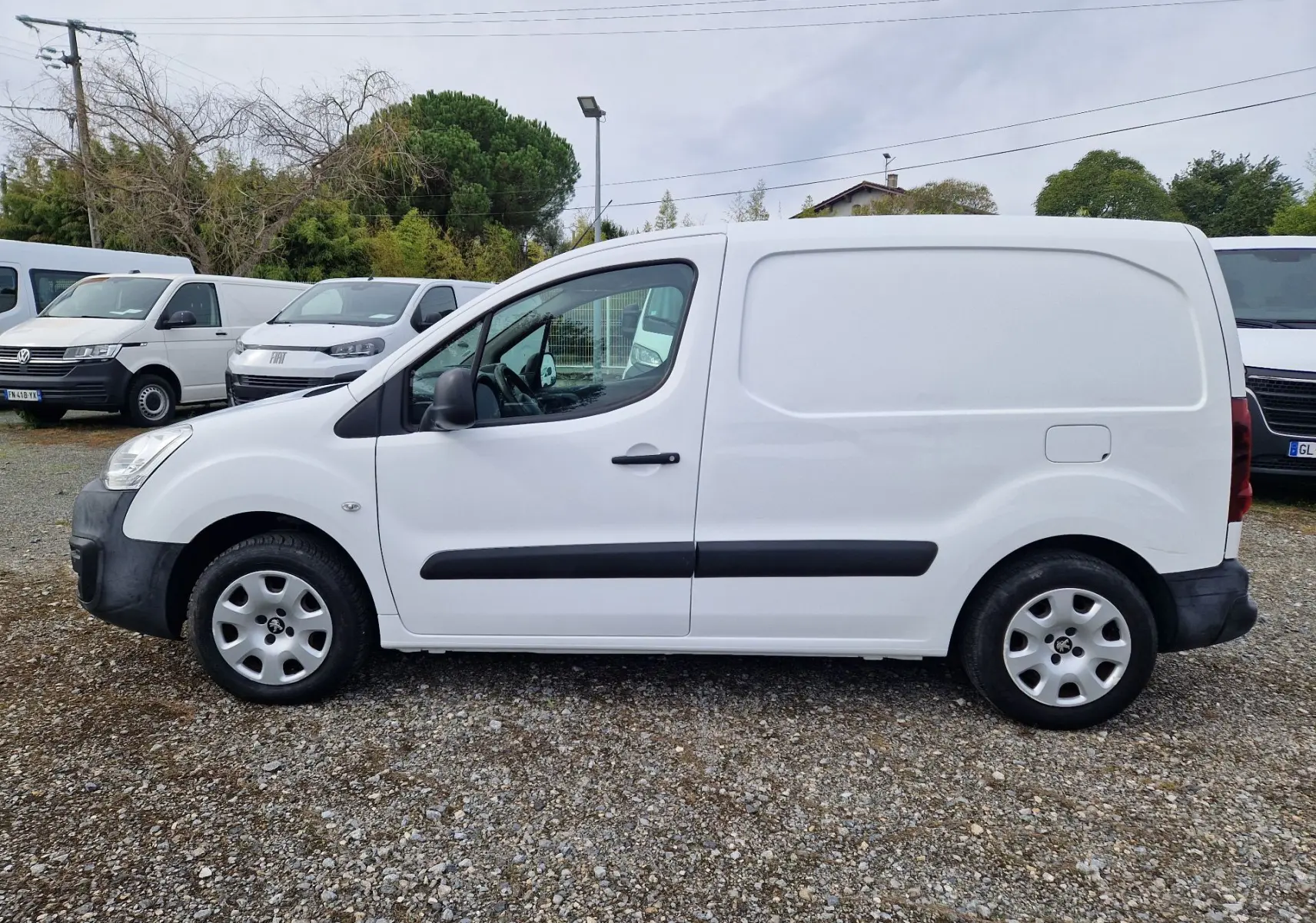 Vue de profil côté gauche d’un Peugeot Partner blanc de 2017 avec protections noires et jantes acier.