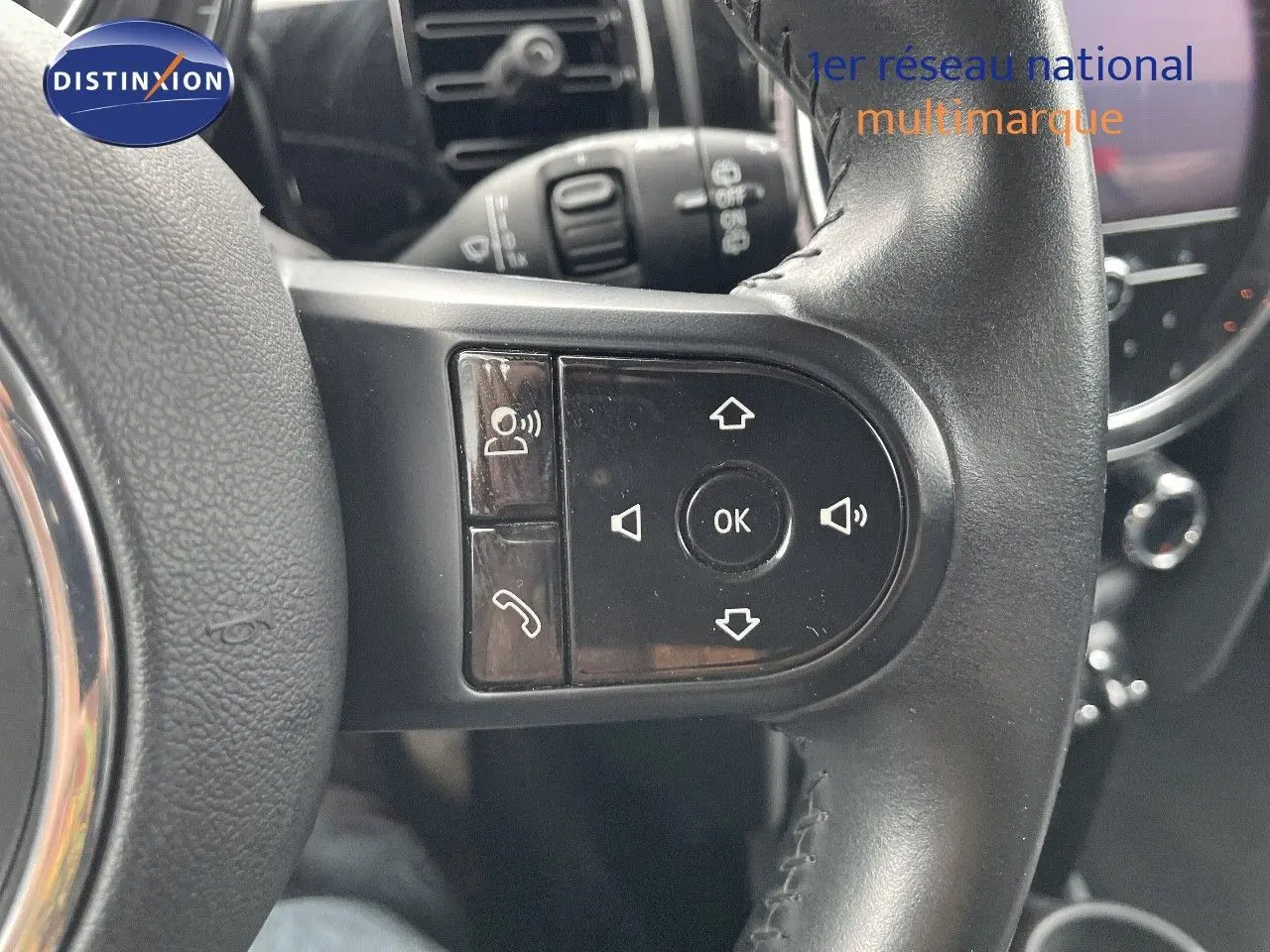 Gros plan sur les commandes du volant d'une MINI 1.5 136CH STEPTRONIC 2023 en cuir noir, intérieur moderne.
