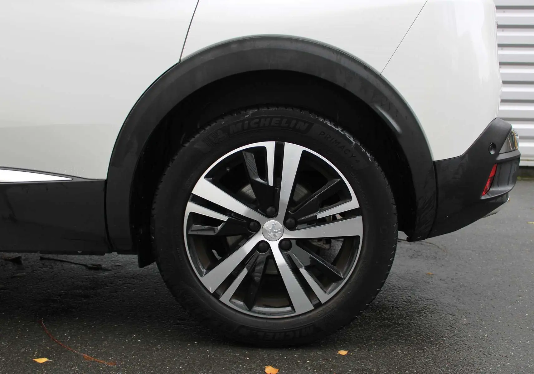 Gros plan sur la roue arrière droite du Peugeot 3008 blanc nacré, soulignant la jante alliage bicolore moderne.