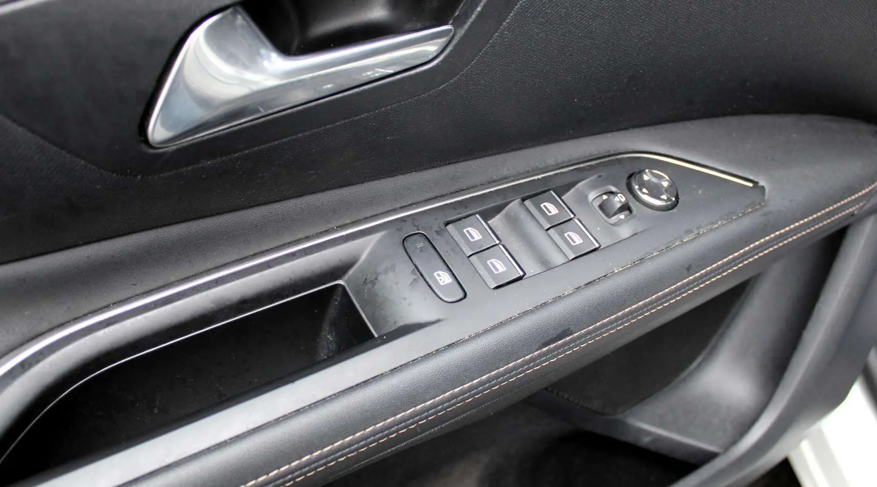 Gros plan sur la commande des vitres et rétroviseurs côté gauche d'une Peugeot 3008 2025 finition GT noire.