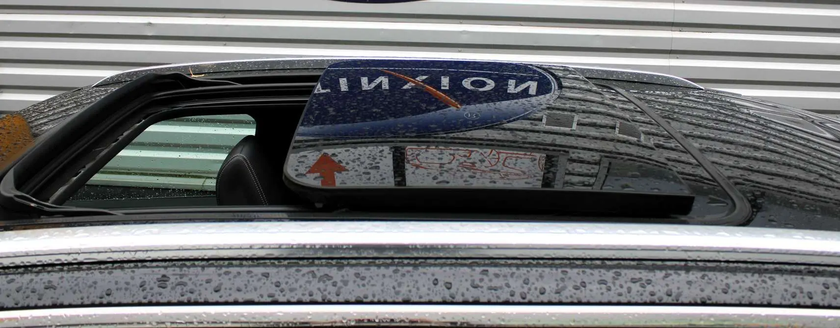 Toit panoramique ouvrant noir avec pluie sur un Peugeot 3008 blanc nacré, vue en gros plan sur l'ouverture.