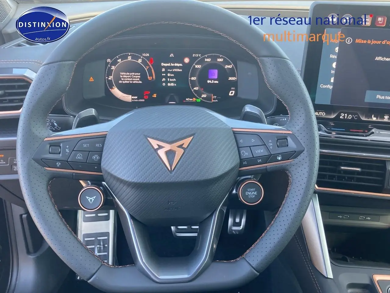 Vue intérieure centrée sur le volant sport cuir noir avec logo Cupra et tableau de bord numérique lumineux.