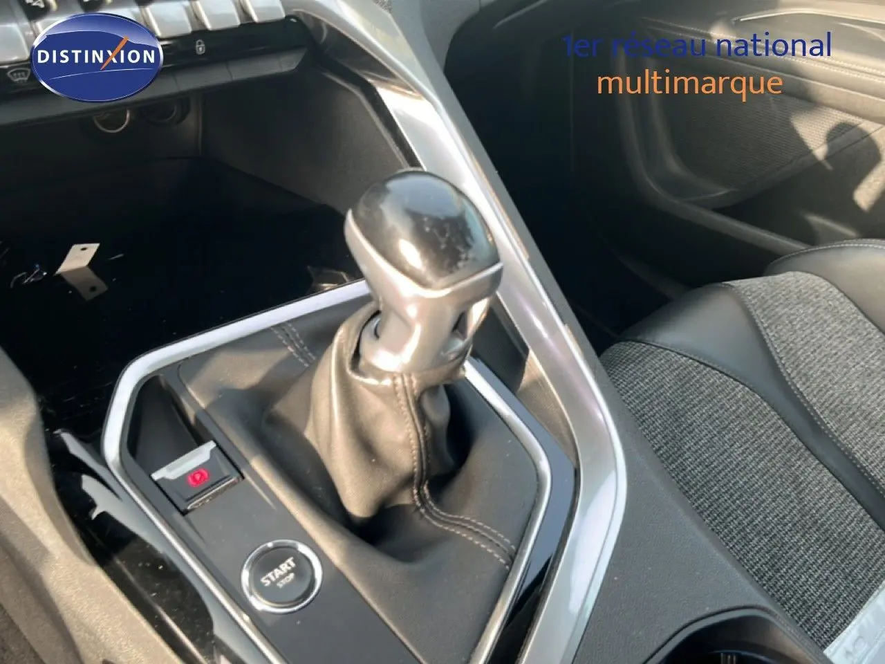 Le levier de vitesse manuel en cuir noir au centre de la console d'une Peugeot 5008 noire, avec bouton start/stop visible.
