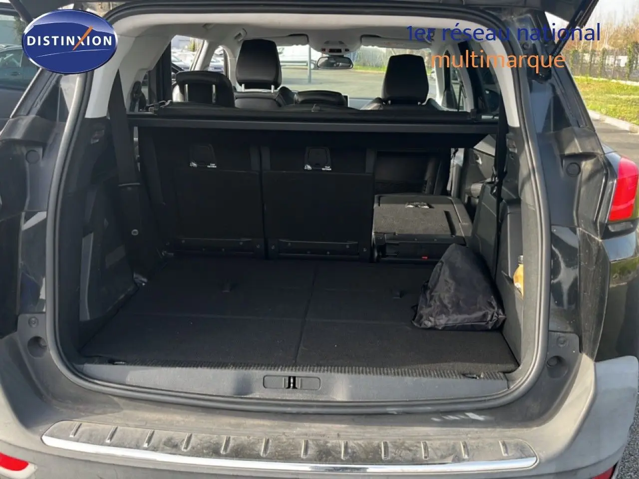 Coffre ouvert en vue arrière d’un Peugeot 5008 noir Perla Nera, montrant l’espace de chargement et sièges rabattus.