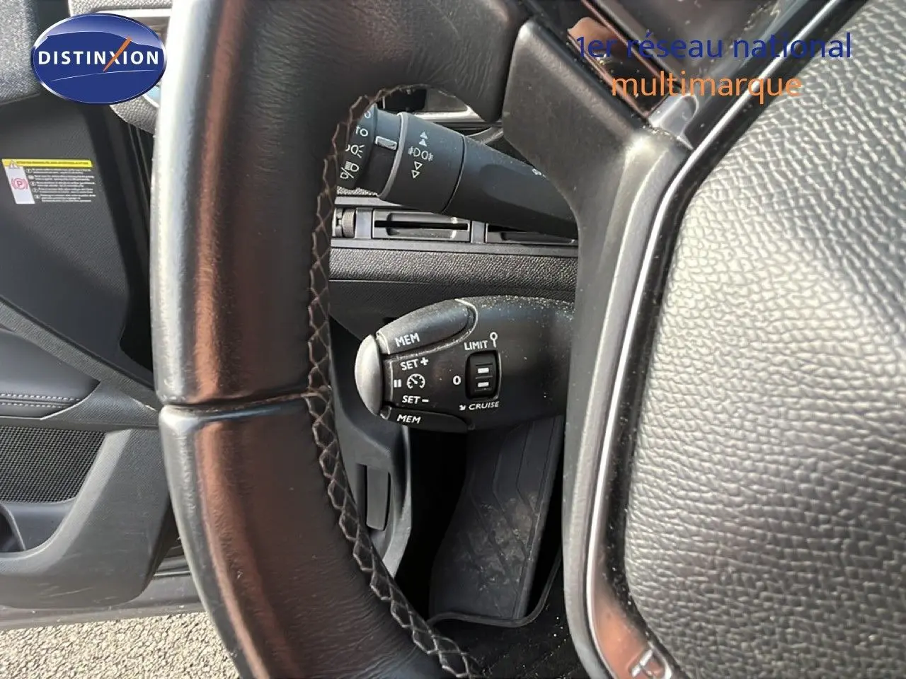 Gros plan sur le volant en cuir noir et la commande de régulateur de vitesse du Peugeot 5008 noir Perla Nera, vue côté conducteur.