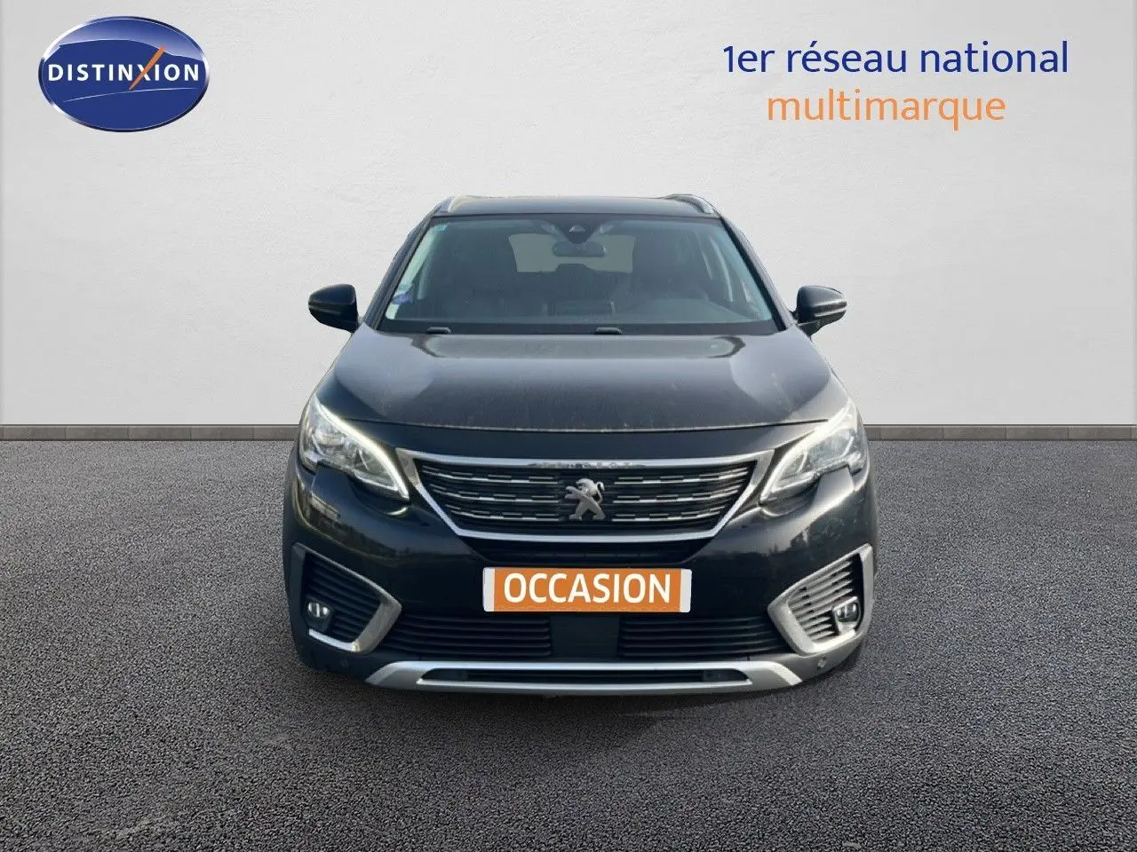 Vue frontale d’un Peugeot 5008 noir Perla Nera avec calandre chromée et feux LED allumés sur fond neutre.