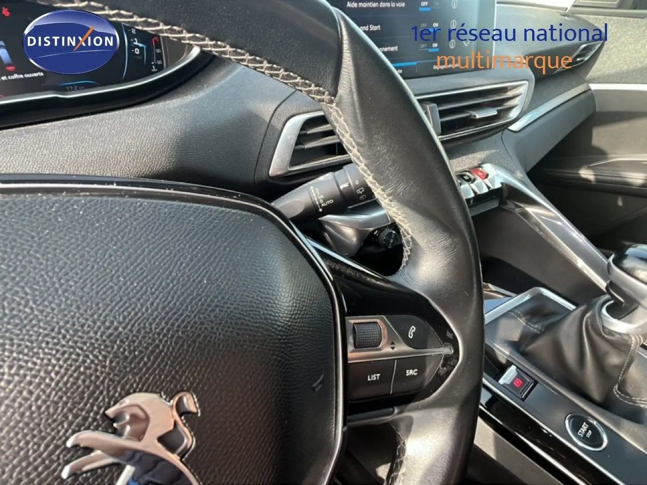 Vue rapprochée de l’intérieur du Peugeot 5008 noir, montrant le volant cuir, la console centrale et le levier de vitesse manuel.