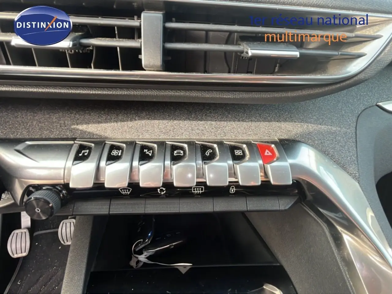 Gros plan sur la rangée de boutons argentés et rouges du tableau de bord intérieur du Peugeot 5008 noir Perla Nera.