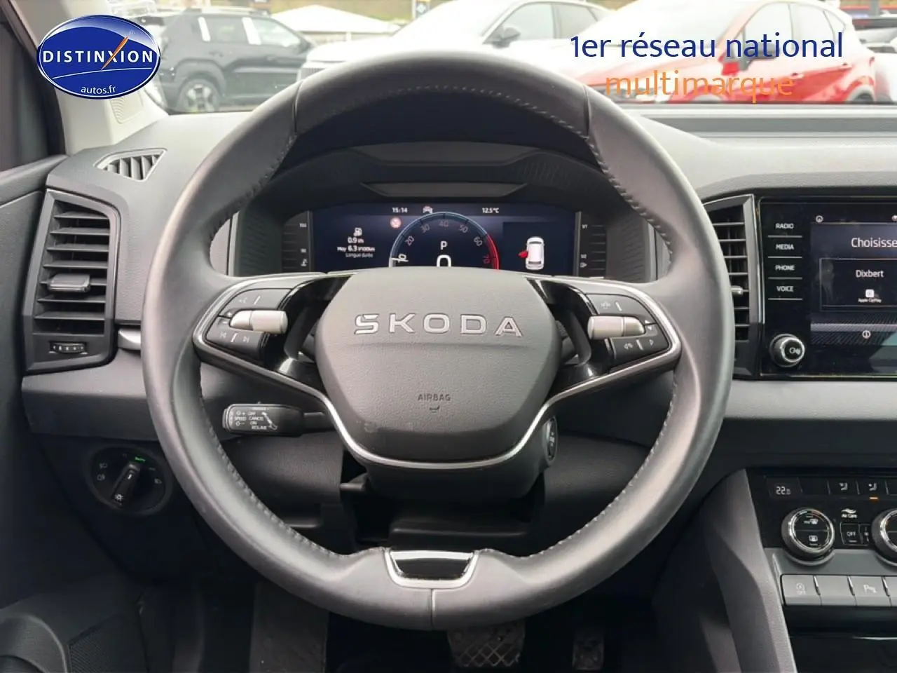 Vue intérieure centrée sur le volant cuir SKODA avec tableau de bord numérique et écran tactile à droite.