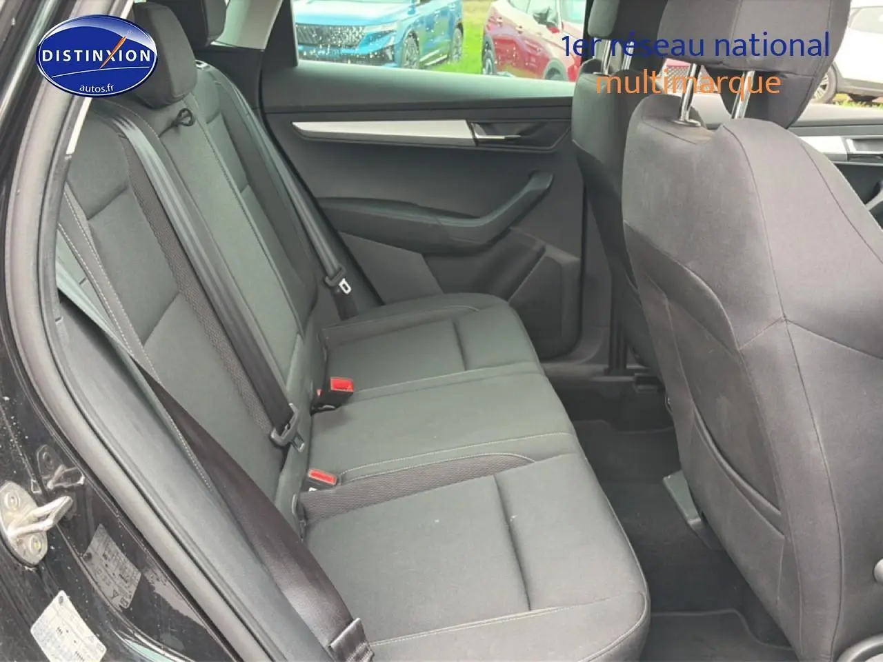 Vue latérale intérieure du siège arrière noir du Skoda Karoq 2025 avec ceintures et portes ouvertes.