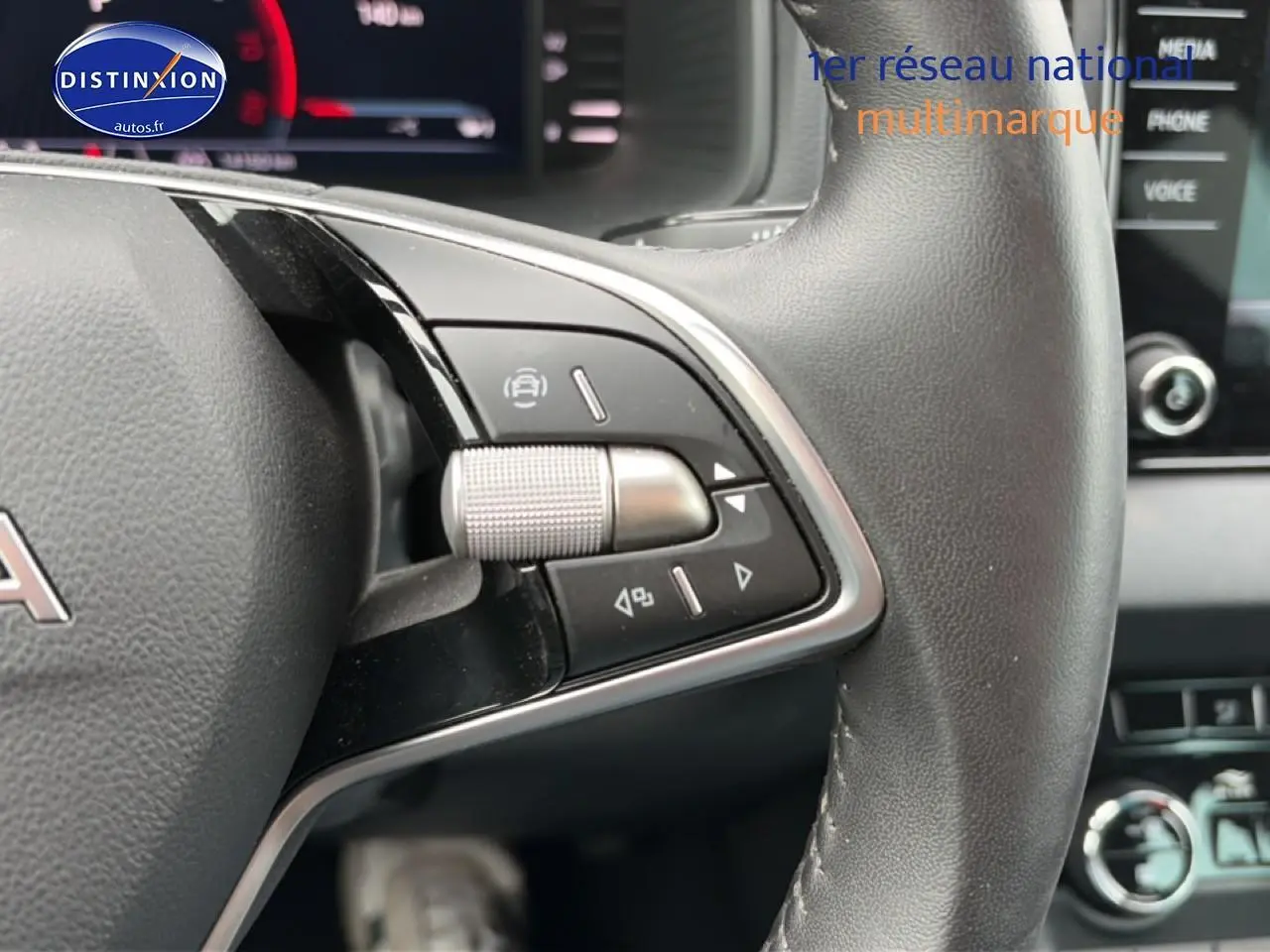 Gros plan sur les commandes à droite du volant cuir noir d’un Skoda Karoq 2025, avec tableau de bord et écran tactile en arrière-plan.