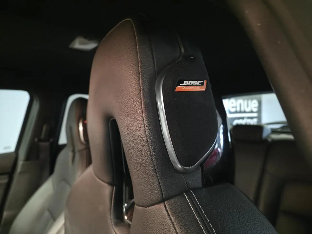 Gros plan sur l’appui-tête avant en cuir noir avec haut-parleur Bose intégré dans un Nissan Juke 2024.