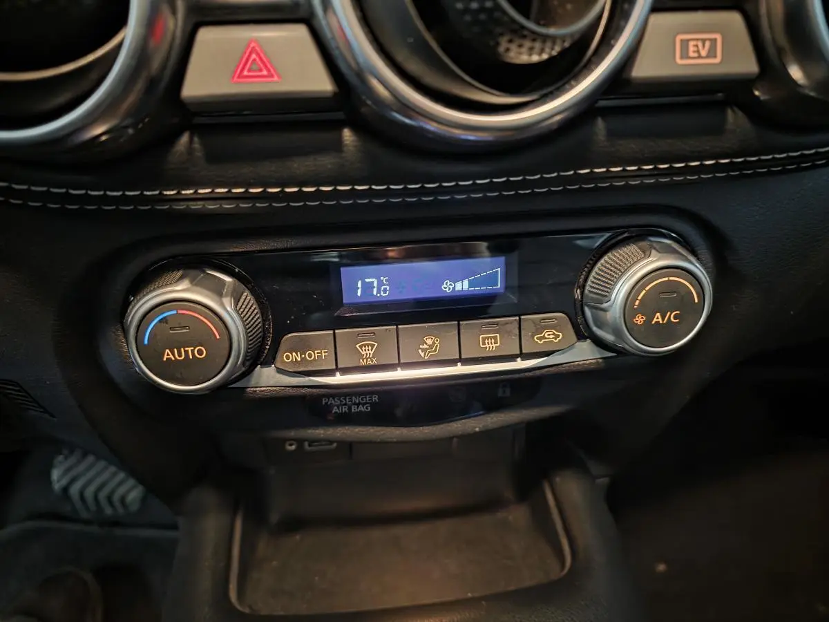 Gros plan sur la console centrale du Nissan Juke 2024, montrant la climatisation automatique avec affichage digital à 17,6°C.