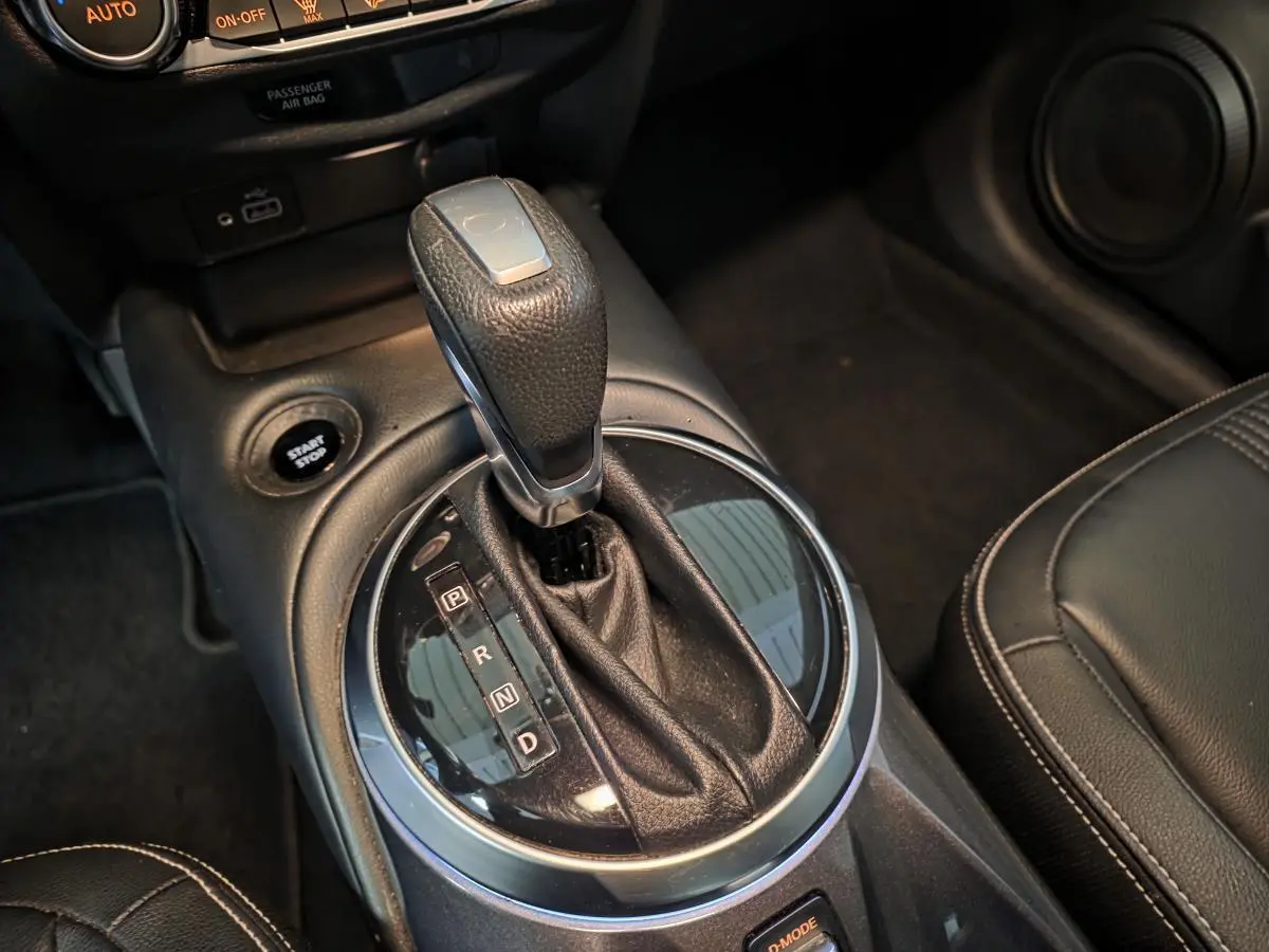 Gros plan sur le levier de vitesses cuir noir de la Nissan Juke 1.6 Hybrid 2024 avec bouton Start/Stop visible.