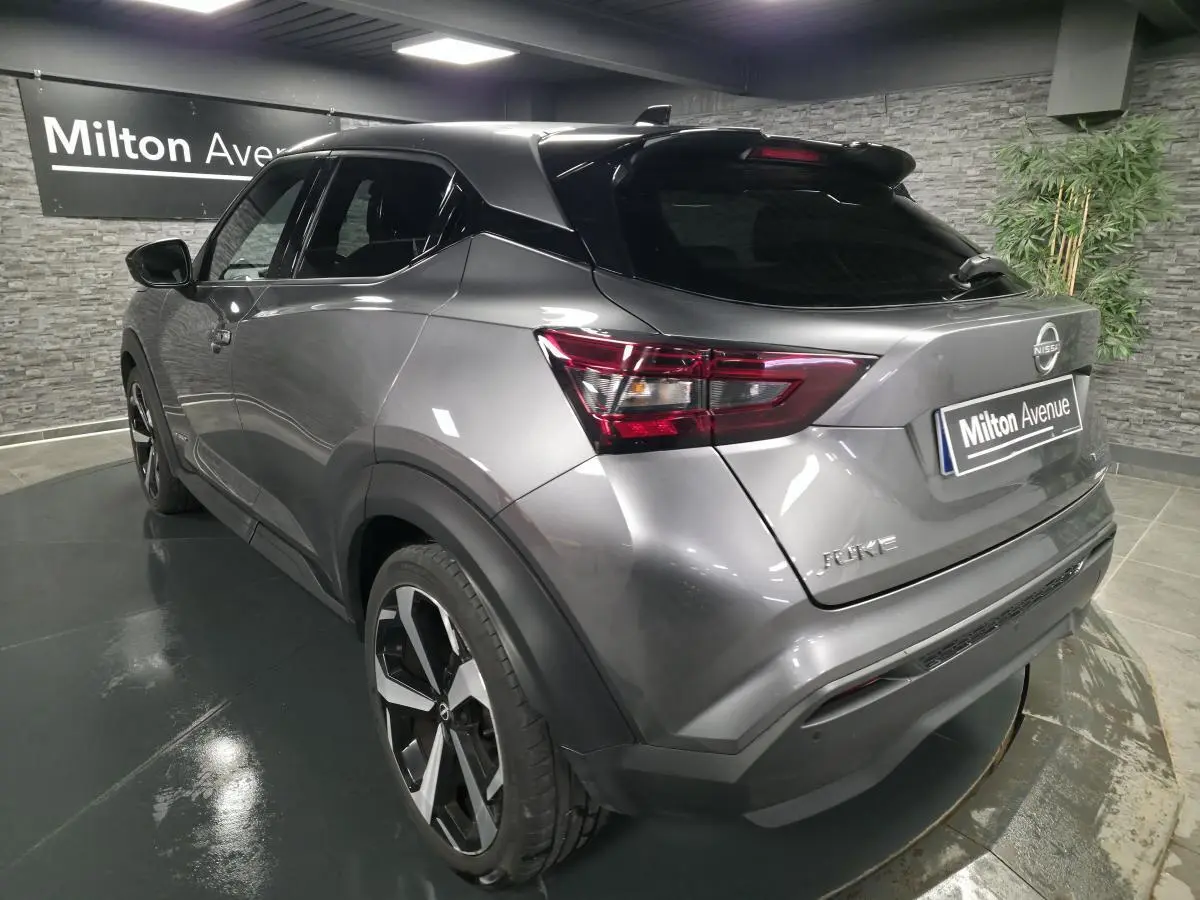 Nissan Juke gris métallisé en 3/4 arrière droit, avec jantes alliage noires et toit noir brillant.
